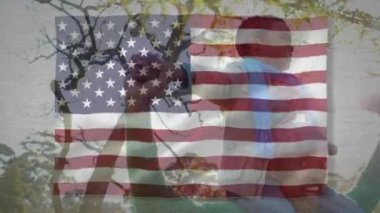 Oğlunu omuzlarında taşıyan Afro-Amerikan bir adamın üzerinde sallanan Amerikan bayrağının animasyonu. Amerika Birleşik Devletleri bayrağı ve tatil konsepti dijital kompozisyon.