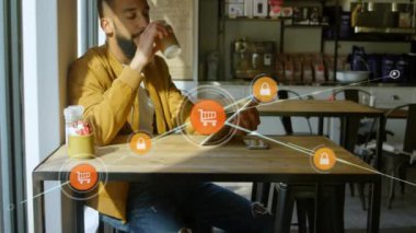 Melez bir ırk adamının, tabletini bağlantı ağlarıyla yüzen simgelerin üzerinde kullanmasının animasyonu. Küresel ağ ve bağlantı konsepti dijital olarak oluşturuldu.