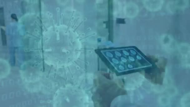 Animation de cellules covid-19 flottant au-dessus d'une vue arrière d'un travailleur de santé caucasien masculin marchant dans une salle d'hôpital et utilisant une tablette. Coronavirus Covid-19 pandémie concept composite numérique.