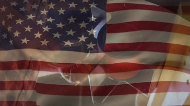 Arka planda öğütücü kullanarak atölyede çalışan adamın üzerinde Amerikan bayrağının dalgalanması. Amerikan toplumu kalkınma vatanseverlik kavramı dijital kompozisyon.