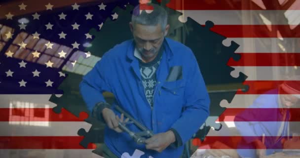 背景には工場で働くシニア ミクストレースマンのパズルピースで形成されたアメリカ国旗のアニメーション アメリカ社会の発展愛国心の概念デジタル構成 — ストック動画