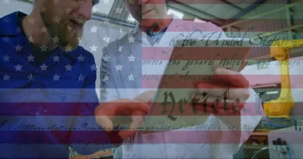 背景に働く2人の男性と工場でアメリカの憲法のテキストを振ってアメリカの国旗のアニメーション アメリカ社会の発展愛国心の概念デジタル構成 — ストック動画