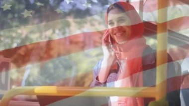 Amerikan bayrağının arka planda akıllı telefon kullanarak tesettürlü melez kadın üzerinde dalgalanması. Amerikan toplumu çeşitlilik kavramı dijital kompozisyon.