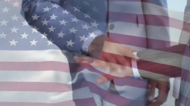 Arka planda el ele tutuşan çok ırklı iş adamları ve iş kadınları üzerinde dalgalanan Amerikan bayrağının animasyonu. Amerikan toplumu çeşitlilik kavramı dijital kompozisyon.
