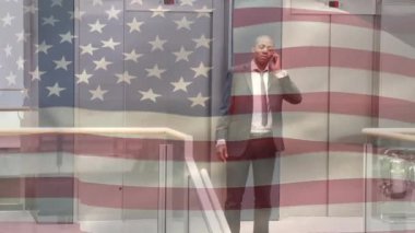 Amerikan bayrağının Afrika kökenli Amerikalı iş adamının arka plandaki merdivenlerden inerken akıllı telefondan konuşmasının animasyonu. Amerikan toplumu çeşitlilik kavramı dijital kompozisyon.