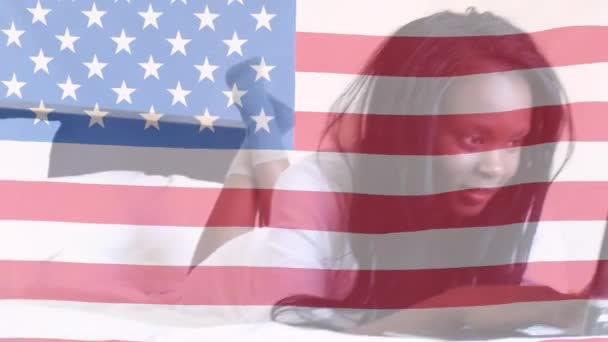 Animación Bandera Estadounidense Ondeando Sobre Mujer Afroamericana Feliz Acostada Cama — Vídeo de stock