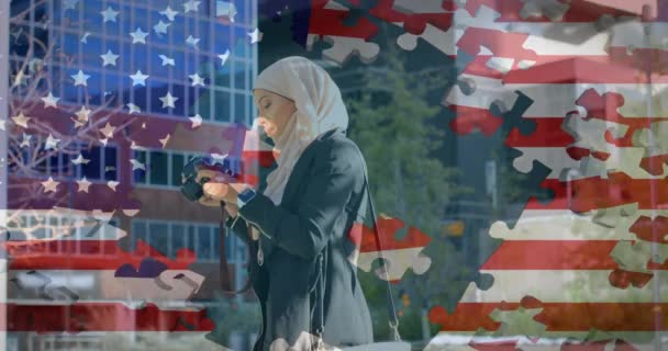 Animace americké vlajky mávající puzzle odhalující smíšenou závodní ženu v hidžábu fotografování s kamerou v pozadí. Americká společnost rozmanitost koncept digitální kompozice.