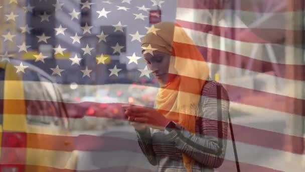 スマートフォンを使ってヒジャーブの女性に手を振って 背景の時間を確認するアメリカ国旗のアニメーション アメリカ社会の多様性の概念デジタル組成 — ストック動画