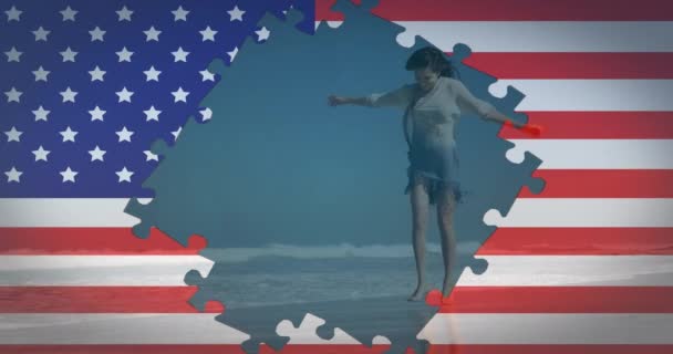 背景には 夏休みの海辺でビーチで踊る女性の姿が描かれたジグソーパズルで手を振っているアメリカ国旗のアニメーション アメリカ社会の多様性の概念デジタル組成 — ストック動画