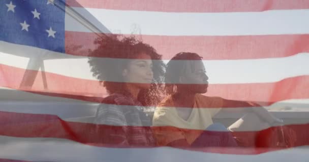 背景の夏休みのロードトリップでは ビーチで混合レースカップルに手を振っているアメリカの国旗のアニメーション アメリカ社会の多様性の概念デジタル組成 — ストック動画