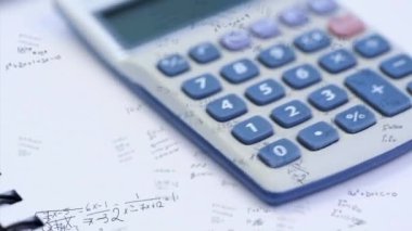 Matematiksel formüllerin hesap makinesi, defter ve beyaz zemin üzerinde dönen kalemlerin animasyonu. Eğitim kavramının dijital ortamda çözülmesi sorunu.