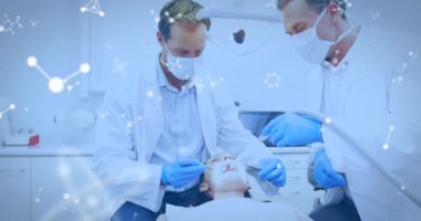 Dişçi koltuğunda hasta tedavi eden yüz maskeli iki erkek diş hekiminin üzerinden akan moleküllerin animasyonu. Tıbbi diş tedavisi Covid 19 koronavirüs koruma konsepti dijital bileşik.