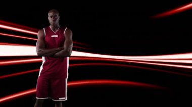 Siyah arka planda kırmızı ışıkta kollarını kavuşturan erkek basketbolcunun dijital videosu.