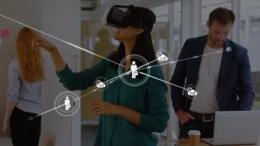 Sanal gerçeklik kulaklığı takan ve meslektaşları tarafından izlenen bir kadının üzerinden veri transferi yapan bir ikon ağının animasyonu. Dijital arayüz VR konsepti, dijital bileşik.