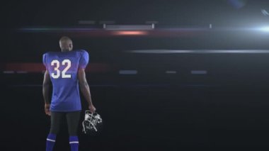 Erkek rugby oyuncusunun siyah arkaplana karşı bir kask ve parlayan ışık noktası tutarken çekilmiş dijital kompozit videosu