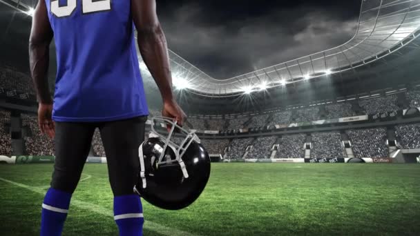 背景にスポーツスタジアムに対するヘルメットを保持男性ラグビー選手の低セクションの背面ビューのデジタル複合ビデオ — ストック動画