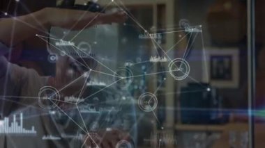 Sanal gerçeklik kulaklığı takan ve sanal arayüzden hoşlanan bir adamın üzerinde hareket eden bağlı simgelerden oluşan bir ağın animasyonu. Dijital arayüz VR konsepti, dijital bileşik.