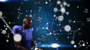 Moleküler yapıların üzerinde kask takan erkek rugby oyuncusunun dijital videosu ve mavi arka planda dönen DNA yapısı. Spor fitness konsepti dijital kompozit