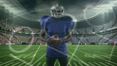 Arka planda erkek rugby oyuncusunun rugby topunu stadyuma karşı tutarken çekilmiş dijital video. Spor fitness konsepti dijital kompozit