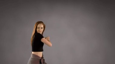 Gri arka planda dans eden genç bir kadının dijital videosu. Yaratıcı ifade, özgürlük, gençlik enerjisi, moda, dans konsepti