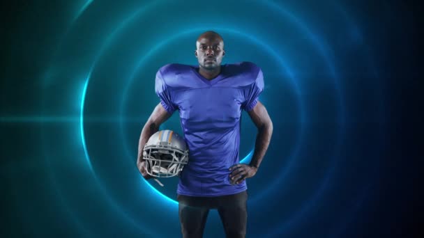 数字合成视频的男性橄榄球运动员持有头盔蓝色发光圈在黑色背景 运动健美概念数码复合材料 — 图库视频影像