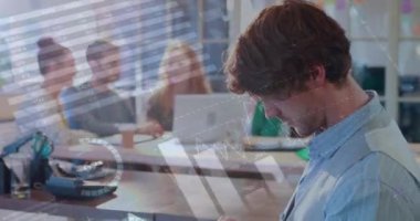 Sıradan bir ofiste arka planda meslektaşlarıyla tablet bilgisayar kullanan gülümseyen bir adam için grafiklerin, verilerin ve dijital arayüzün animasyonu. Küresel dijital ağ konsepti dijital bileşimi.