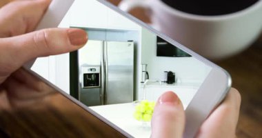 Ekranda gösterilen ev mutfağı içerisindeki akıllı telefonu kullanan kişinin animasyonu. Çevrimiçi alışveriş evi dekorasyonu konsepti dijital kompozit.