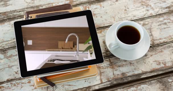 木製の表面にコーヒーカップで画面上に表示される家のキッチンインテリアとデジタルタブレットのアニメーション オンラインショッピングハウス装飾コンセプトデジタル複合体 — ストック動画
