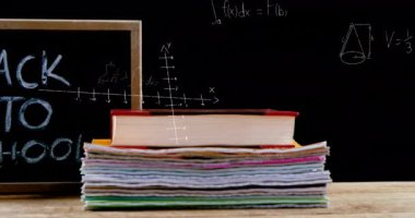 Matematiksel denklemlerin animasyonu arka planda renkli kalemler ve kitaplarla Okula Dönüş metninin üzerinde yüzüyor. Okul kavramına geri dönüş dijital olarak oluşturulan imaj.