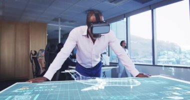 VR kulaklık takan bir iş adamının animasyonu. Masada 3D planı var.