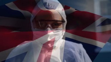 İngiliz bayrağının beyaz kadın bilim adamının koruyucu giysiler giyip kameraya bakıp gülümsediği animasyon. Covid-19 Coronavirus Ulusal Sağlık Güvenliği Konsepti Dijital Kompozit