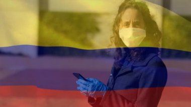 Kolombiya bayrağının beyaz kadın üzerinde sallanıp maske taktığı ve akıllı telefon kullandığı bir animasyon. Covid-19 Coronavirus Ulusal Sağlık Güvenliği Konsepti Dijital Kompozit