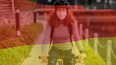 Alman bayrağının beyaz kadın üzerinde sallanışı, maske takması ve bisiklete binmesi. Covid-19 Coronavirus Ulusal Sağlık Güvenliği Konsepti Dijital Kompozit
