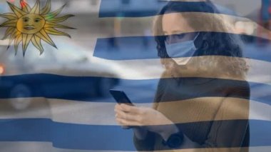 Uruguay bayrağının, yüz maskesi takan ve akıllı telefon kullanan beyaz bir kadının üzerinde dalgalanması. Covid-19 Coronavirus Ulusal Sağlık Güvenliği Konsepti Dijital Kompozit