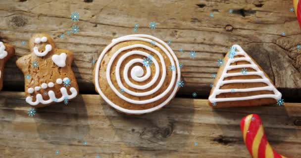 圣诞姜饼人饼干和糖果手杖在木制表面上飘落的雪花的动画 圣诞庆祝概念数字生成的图像 — 图库视频影像