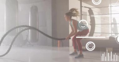 Veri işleme ve beyaz kadının spor salonunda replik kullanması üzerine diyagramların animasyonu. Küresel spor ve dijital arayüz kavramı dijital olarak oluşturulmuş video.