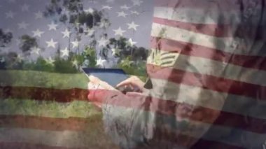 Kırsal kesimde tablet kullanan beyaz erkek asker üzerinde Amerikan bayrağı canlandırması. Amerikan, vatanseverlik, kutlama, askerlik, ordu, bağlantı ve iletişim, dijital olarak oluşturulmuş video.