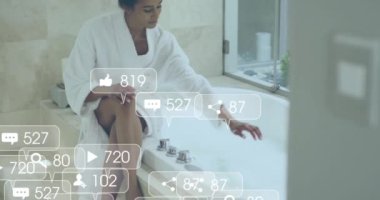 Banyo yapan bornozlu kadın hakkında sosyal medya bildirimleri. Yaşam tarzı, kişisel bakım, rahatlama, dijital arayüz, sosyal ağ ve iletişim, dijital olarak oluşturulmuş video.