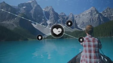 Dağlardaki gölde kayıktaki beyaz adamın üzerindeki ikonlarla olan bağlantıların animasyonu. Dijital olarak oluşturulmuş küresel bağlantılar, doğa ve dijital arayüz kavramı.