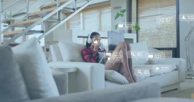 Evde tablet kullanan melez bir kadın hakkında sosyal medya bildirimleri. Yaşam tarzı, rahatlama, dijital arayüz, sosyal ağ ve iletişim, dijital olarak oluşturulmuş video.