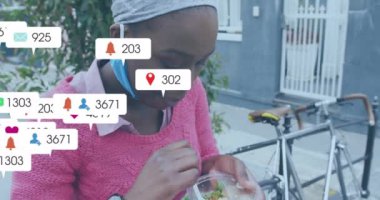 Afro-Amerikan kadınlarının şehir caddesinde yemek yemesi ile ilgili medya bildirimleri. Yaz, sağlıklı yaşam tarzı, şehir, dijital arayüz, sosyal ağ ve iletişim, dijital olarak oluşturulmuş video.