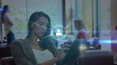 Sıradan bir ofiste tablet kullanan iki ırklı iş kadınının insan ikonlarının canlandırılması. Bağlantı, veri, dijital arayüz, iş, yaşam tarzı ve iletişim, dijital olarak oluşturulmuş video.