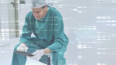 Ameliyat odasında tablet kullanan beyaz erkek cerrahın üzerine düşen şekillerin animasyonu. Küresel tıp ve dijital arayüz kavramı dijital olarak oluşturulmuş video.