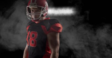 Arka planda dumanların ve spot ışıklarının üzerindeki Amerikan futbolcusunun görüntüsü. Spor ve rekabet konsepti dijital olarak oluşturulmuş imaj.