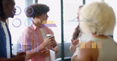 Konuşmacı esmer hareketlerini dinliyor, kahve içiyor ve ofis incelemesi sırasında tablolara işaret ediyor. İşbirliği, takım çalışması, veri analizi, modern ofis, iş toplantısı, yenilik, iletişim