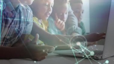 Öğretmen dizüstü bilgisayarı işaret ediyor ve çocukların ağ kaplamasına tıklayarak yazmalarına rehberlik ediyor. İşbirliği, eğitim, dijital, öğrenme, etkileşim, teknoloji, sınıf