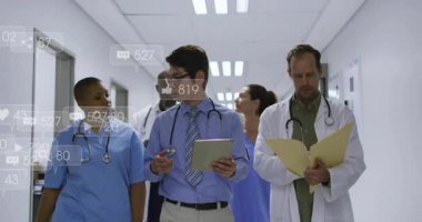 Sosyal medya simgeleri zayıflarken tıbbi ekip koridorunda hasta verilerini tartışıyor. Sağlık, işbirliği, profesyonellik, yenilik, takım çalışması, klinik, dijital