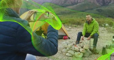 Kadın fotoğrafçı akıllı telefon yetiştiriyor, adamı yakalıyor, ateş yakıyor ve kamp gezisini belgeliyor. Macera, açık hava, kırsal, yaşam tarzı, keşif, manzara, sükunet