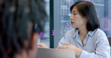 Mali işler müdürü, mali verileri açıklarken para birimi simgelerini işaret ederek meslektaşına dönüyor. İş, işbirliği, şirket, sunum, takım çalışması, yenilik, analitik