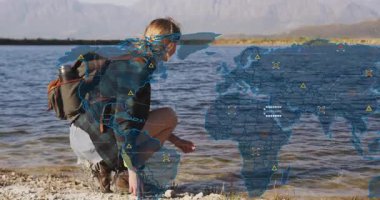 Kadın göl kıyısı kepçesi taşına yaklaşıyor botları ayarlıyor ve yol haritasını takip ediyor. Macera, keşif, doğa, manzara, açık hava, yürüyüş, sükunet